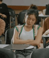 a woman is sitting at a desk in a classroom with her eyes closed .