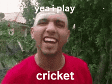 a bald man in a red shirt is smiling and says yea i play cricket