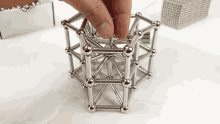 a person is playing with a metal toy that looks like a cube