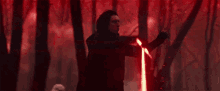 a storm trooper is fighting a man with a red lightsaber in a forest