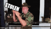 a man in a camouflage uniform is holding a sign that says stolen
