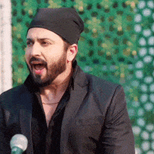 a man with a beard is wearing a black hat and a black suit .