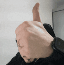a person giving a thumbs up sign with a watch on their wrist