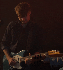 a man playing a guitar with a microphone in the background