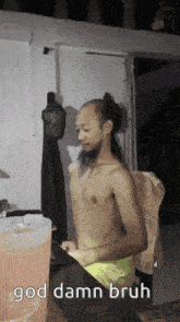 a shirtless man with a beard is standing in front of a pink container that says god damn bruh