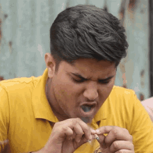 a man wearing a yellow shirt is smoking a cigarette