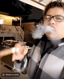 a man wearing glasses is smoking a cigar with the caption añadir un lente