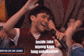 a man laughs while holding a microphone that says inside joke