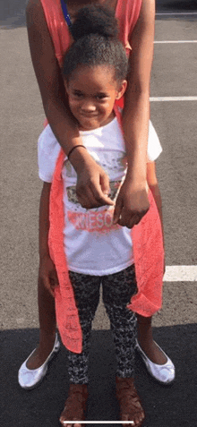 a woman is holding a little girl on her shoulders .