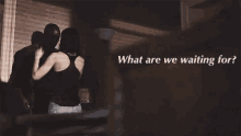 a man and a woman are standing in a dark room with the words " what are we waiting for " on the bottom