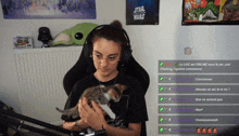 a woman wearing headphones is holding a kitten in front of a star wars poster