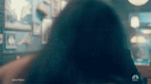 a woman is sitting at a table in a dark room looking at a phone .