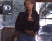 a woman in a black jacket is standing in front of a window in a restaurant .