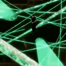 a man in a black shirt is running through a maze of green lights .