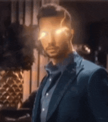 a man in a suit and blue shirt is standing in a room with his eyes glowing .