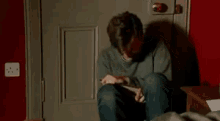 a man is sitting on the floor with his mouth open holding a box .