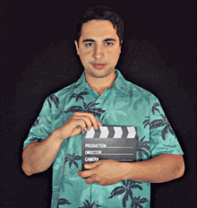 a man in a green shirt holds a clapper board that says production director camera