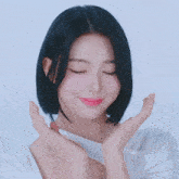 a woman with short black hair is smiling with her eyes closed and her hands on her face .