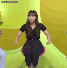 a woman in a black shirt and black pants is sitting on a chair .