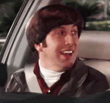 a man is sitting in the back seat of a car with his mouth open .