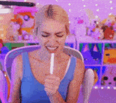 a woman in a blue tank top is holding a white stick in her hand