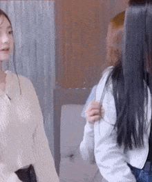 two women are sitting next to each other on a couch talking to each other .