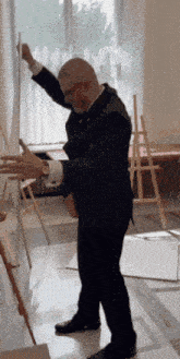 a man in a suit is standing in front of an easel with his arms outstretched