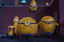 a group of minions are standing in front of a brick wall and a sign that says atlas