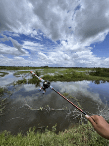 a person is holding a fishing rod in front of a lake