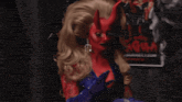 a woman with red horns is standing in front of a movie poster that says ' evil '