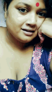 a woman with a red dot on her forehead is wearing a blue top