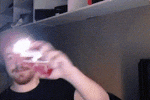 a man in a black shirt is drinking from a glass