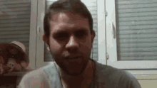a man wearing headphones looks at the camera with a hat in the background