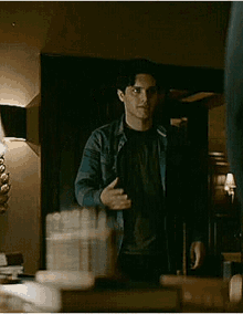a man in a plaid shirt is standing in front of a mirror in a dark room