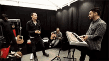 a man is playing a keyboard in a room with other men