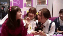 a group of girls are sitting on a couch talking to each other and smiling .