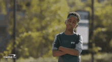 a young boy stands with his arms crossed in front of a capital one sign