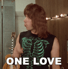 a man in a skeleton shirt is standing in front of a sign that says " one love "
