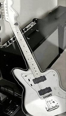 a white electric guitar is sitting next to a black amp