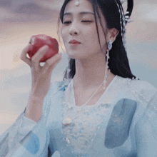 a woman in a blue dress is holding a red apple in her hand