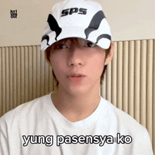 a young man wearing a sps hat and a white shirt