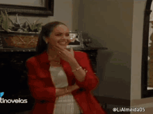 a woman in a red jacket is laughing in front of a fireplace