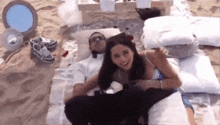 a man and a woman are laying on a blanket in the sand
