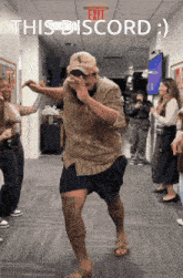 a man in a hat is dancing in a hallway under an exit sign