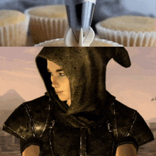 a man wearing a hooded cape is looking at a cupcake