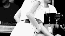 a woman in a white crop top and shorts is standing in front of a camera in a black and white photo .