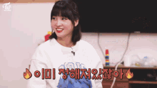 a woman wearing a twice sweatshirt is smiling in front of a flat screen tv
