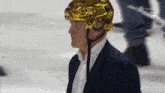 a man wearing a gold helmet and a blue suit stands on a hockey rink
