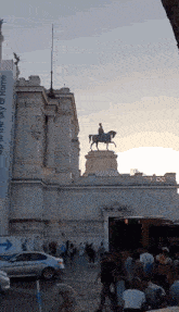 a statue of a man on a horse is in front of a building with a sign that says up to the sky of rome