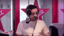 a man wearing headphones is sitting in front of a microphone in a radio studio .